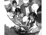Members of a Samaritan family in Palestine are gathered for their Passover feast round the dish of lamb seasoned with bitter herbs. An early photograph.